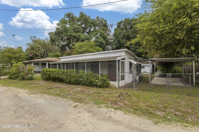 view of property exterior with a sunroom, a carport, and cooling unit