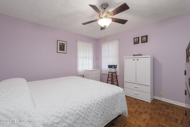 bedroom with a textured ceiling, dark parquet floors, and ceiling fan