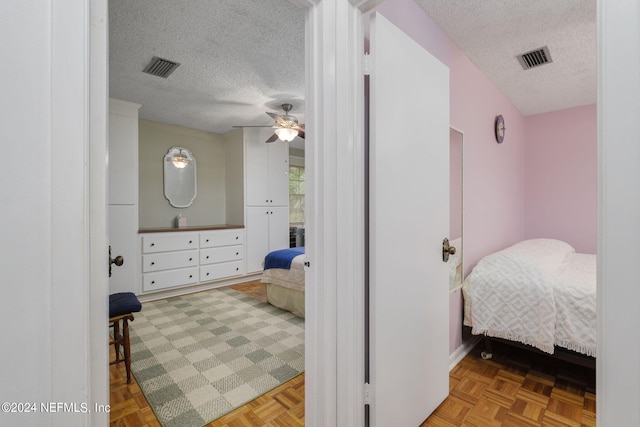 bedroom featuring light parquet flooring, ceiling fan, and a textured ceiling