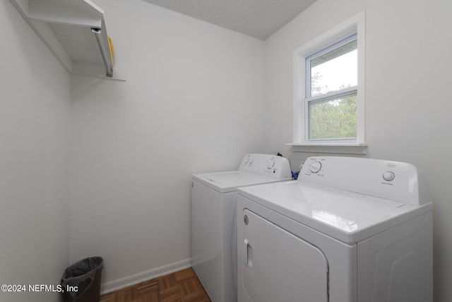 washroom featuring a textured ceiling, washer and clothes dryer, and dark parquet floors