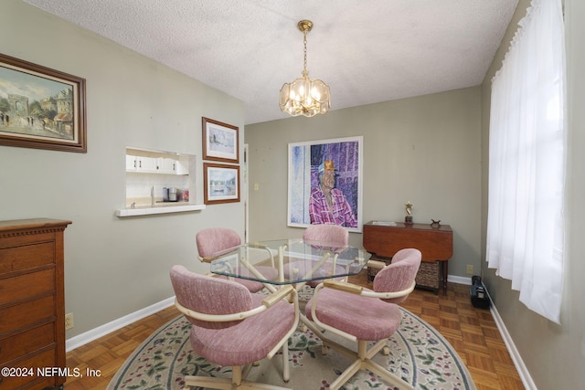 dining area featuring a textured ceiling, parquet flooring, and an inviting chandelier