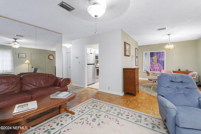 living room featuring a textured ceiling, ceiling fan, and light parquet flooring