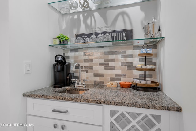 interior space featuring sink, tasteful backsplash, dark stone countertops, and white cabinets