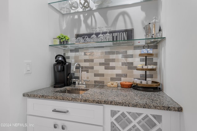 interior space with decorative backsplash, dark stone counters, white cabinets, and a sink