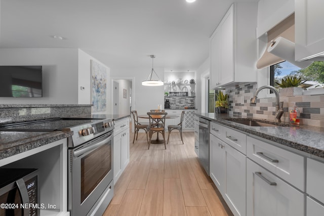 kitchen featuring sink, stainless steel appliances, white cabinets, and dark stone counters