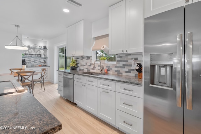 kitchen with sink, appliances with stainless steel finishes, light hardwood / wood-style floors, tasteful backsplash, and white cabinets