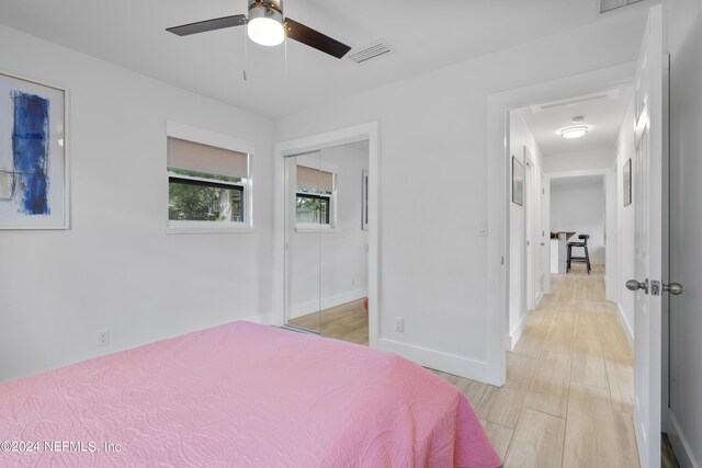 bedroom with light hardwood / wood-style floors, ceiling fan, and a closet