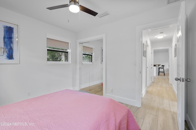 bedroom featuring a ceiling fan, baseboards, light wood finished floors, visible vents, and a closet