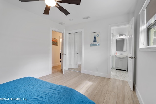 unfurnished bedroom featuring ceiling fan, baseboards, light wood-type flooring, ensuite bath, and a sink