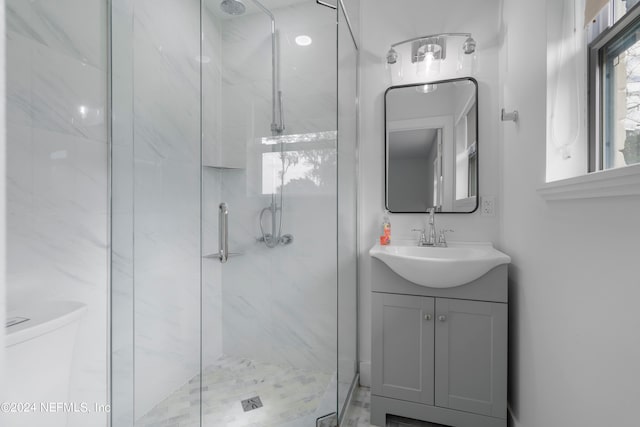 bathroom featuring toilet, vanity, and a shower with shower door