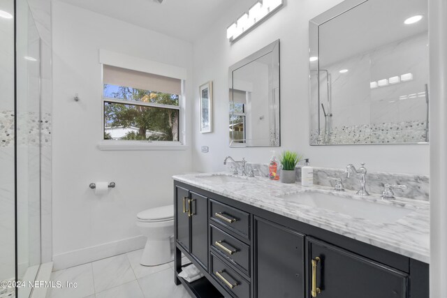 bathroom with tiled shower, toilet, tile patterned flooring, and vanity