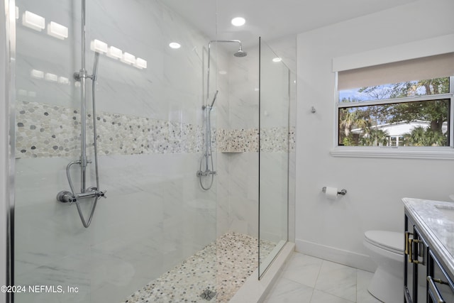 bathroom featuring a marble finish shower, toilet, vanity, and baseboards