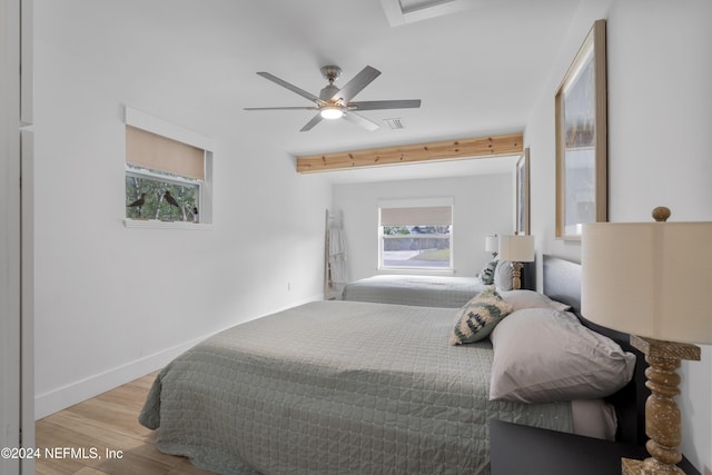 bedroom with visible vents, multiple windows, wood finished floors, and baseboards