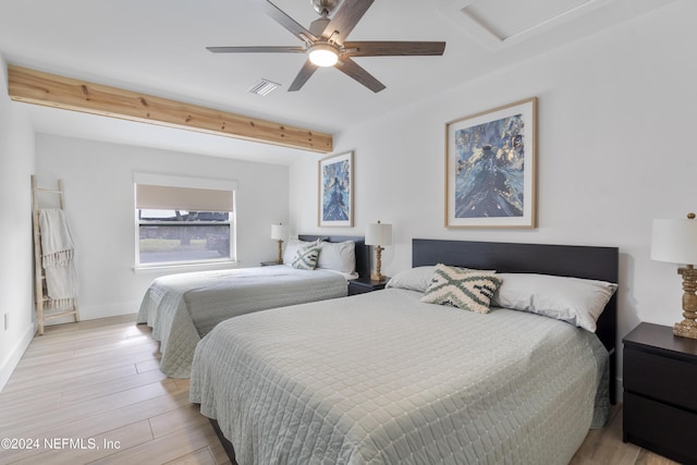 bedroom featuring beam ceiling, visible vents, baseboards, and light wood-style floors