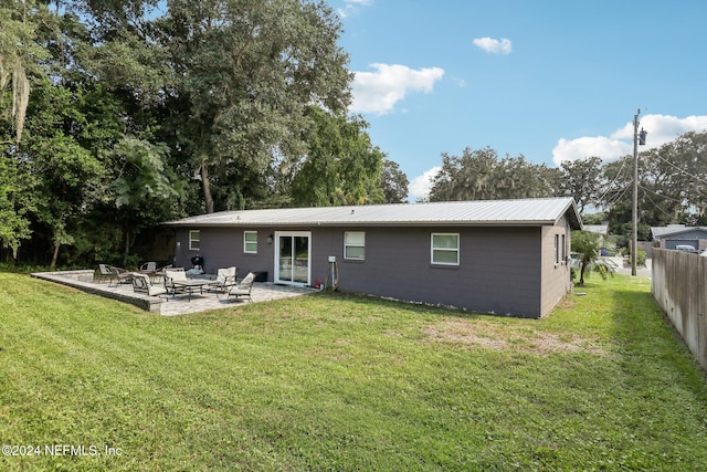 rear view of property featuring a lawn and a patio area