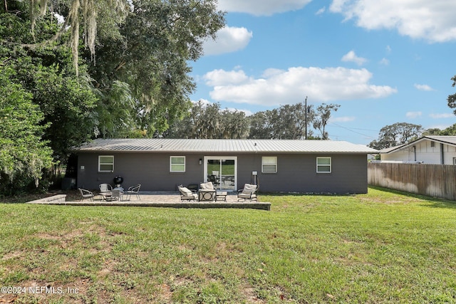 rear view of house featuring a patio area, a lawn, metal roof, and fence