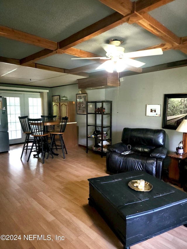 living room featuring beam ceiling, ceiling fan, hardwood / wood-style floors, and a textured ceiling