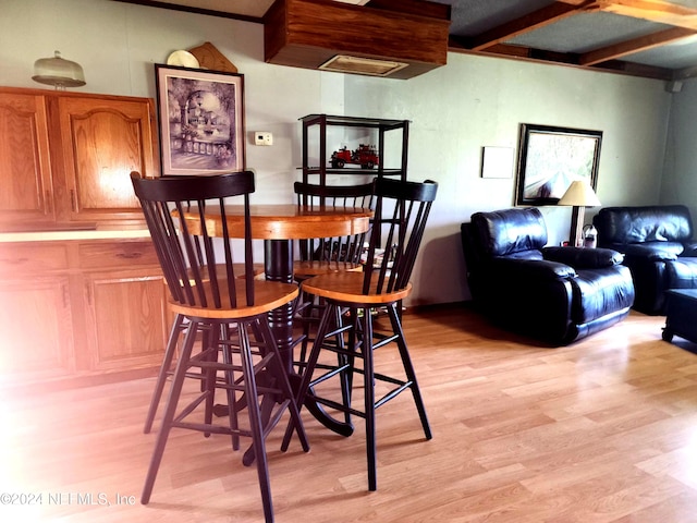 dining area featuring light wood-type flooring and beam ceiling