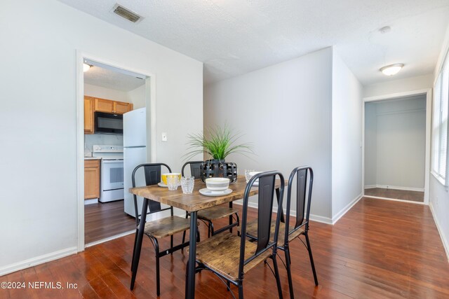 dining area with a textured ceiling and dark hardwood / wood-style flooring