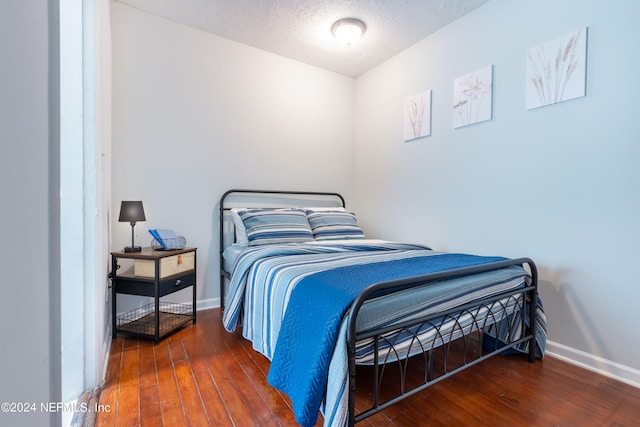 bedroom with dark hardwood / wood-style flooring and a textured ceiling