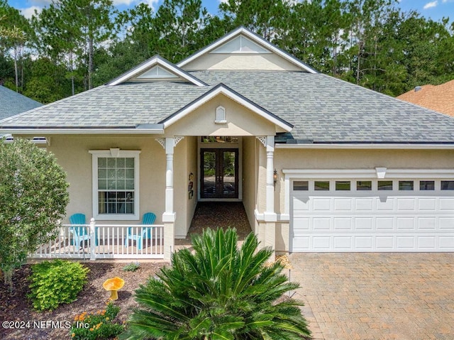 view of front of house with stucco siding, roof with shingles, an attached garage, and french doors