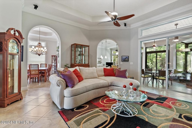 living area with light tile patterned floors, arched walkways, a raised ceiling, and ornamental molding