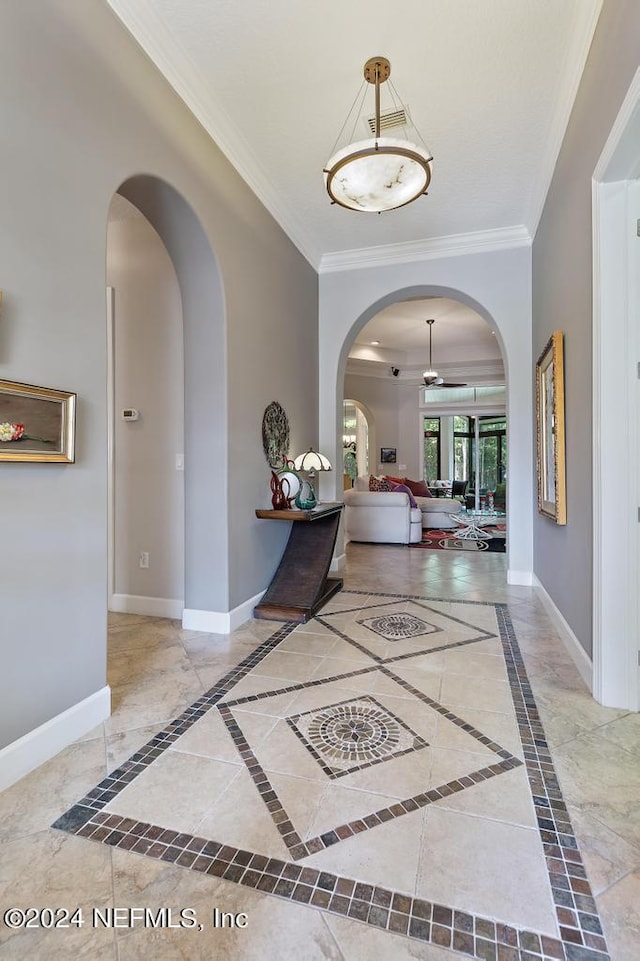 entrance foyer with arched walkways, baseboards, and ornamental molding