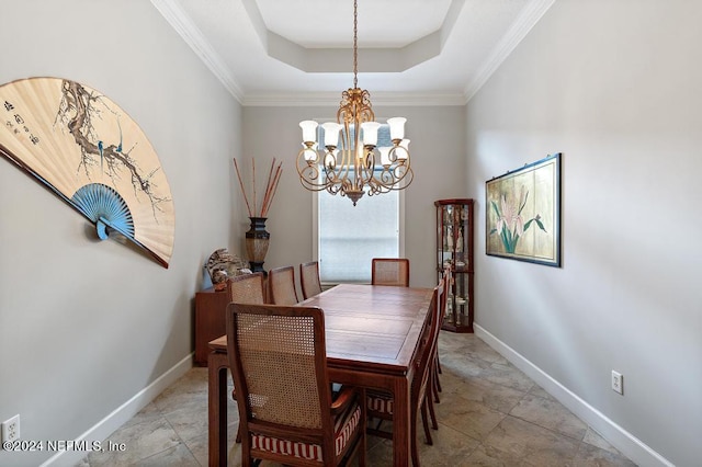 dining room with an inviting chandelier, baseboards, a tray ceiling, and ornamental molding