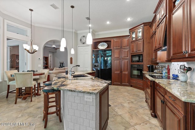 kitchen featuring crown molding, a kitchen breakfast bar, arched walkways, black appliances, and a sink