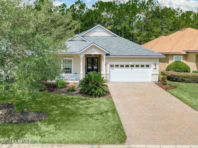 ranch-style home featuring decorative driveway, a porch, a shingled roof, a front yard, and an attached garage