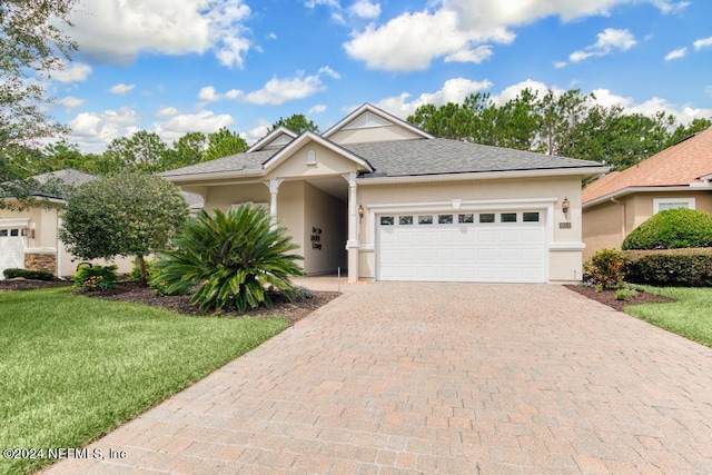 single story home with a front lawn, decorative driveway, an attached garage, and stucco siding