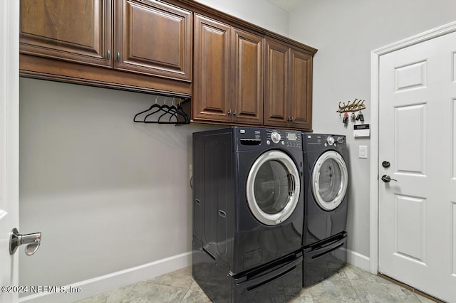 laundry area featuring baseboards, cabinet space, and washing machine and clothes dryer