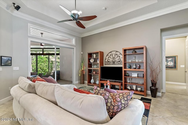 living area with a tray ceiling, baseboards, and crown molding