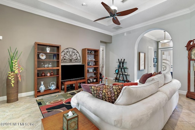 living area with a raised ceiling, arched walkways, crown molding, baseboards, and ceiling fan