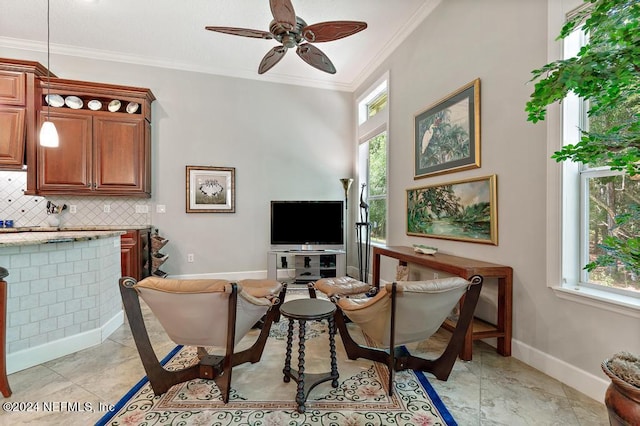 living room featuring baseboards, ornamental molding, and a ceiling fan