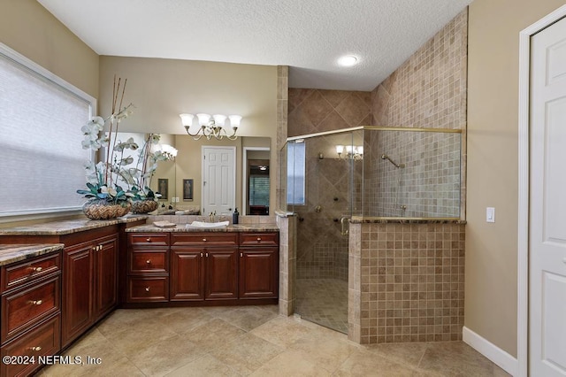 full bathroom with tile patterned flooring, a stall shower, a notable chandelier, a textured ceiling, and vanity