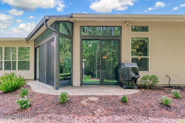 property entrance with stucco siding and a patio