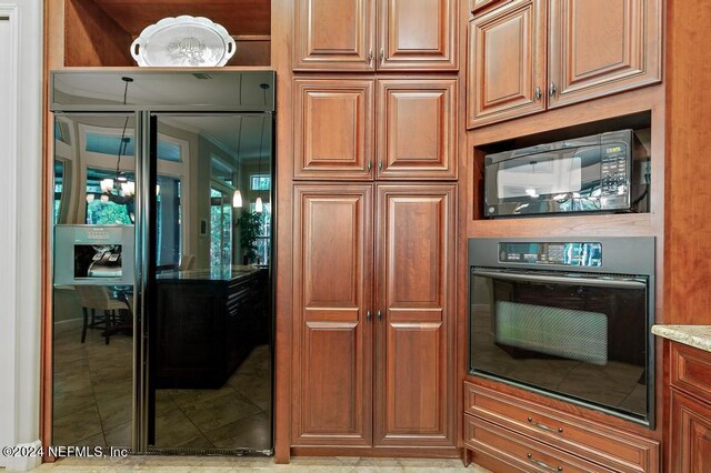 kitchen with light tile patterned floors, brown cabinets, black appliances, and light stone counters