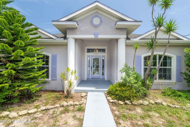 doorway to property with a shingled roof and stucco siding