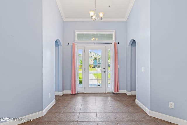 tiled entrance foyer featuring ornamental molding, plenty of natural light, a towering ceiling, and a notable chandelier