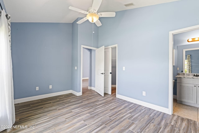 unfurnished bedroom featuring baseboards, visible vents, ensuite bath, wood finished floors, and a sink