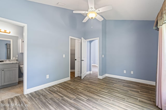 unfurnished bedroom featuring ensuite bath, vaulted ceiling, ceiling fan, and a closet