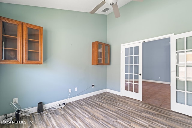 unfurnished room featuring french doors, ceiling fan, wood-type flooring, and vaulted ceiling