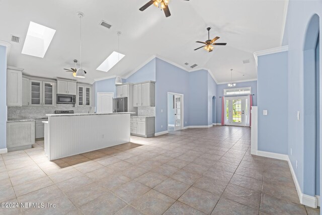 kitchen featuring a kitchen island with sink, appliances with stainless steel finishes, a skylight, and ceiling fan