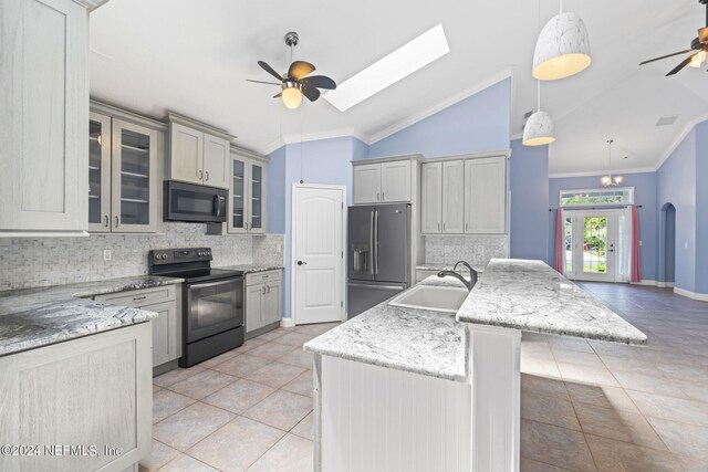 kitchen with black appliances, ceiling fan, sink, and lofted ceiling with skylight