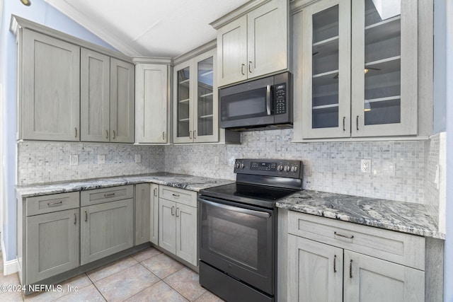 kitchen featuring light tile patterned floors, electric range, vaulted ceiling, backsplash, and stainless steel microwave