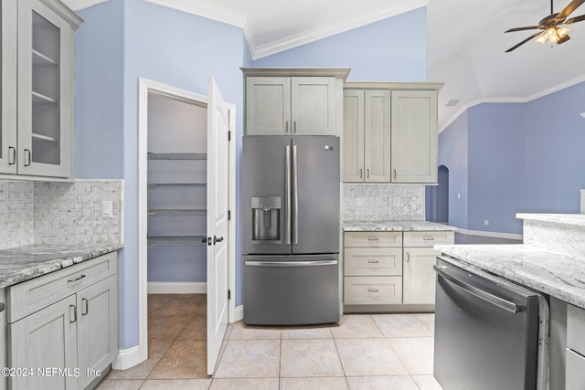 kitchen featuring light tile patterned floors, ceiling fan, stainless steel appliances, vaulted ceiling, and ornamental molding