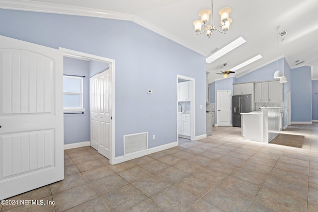 unfurnished living room featuring vaulted ceiling with skylight, visible vents, baseboards, ornamental molding, and ceiling fan with notable chandelier