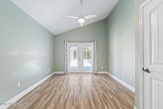 spare room featuring lofted ceiling, ceiling fan, hardwood / wood-style flooring, and french doors