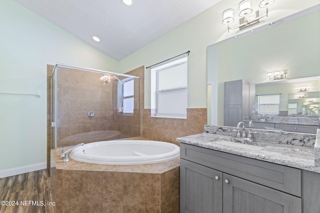 bathroom featuring lofted ceiling, a garden tub, tiled shower, and vanity